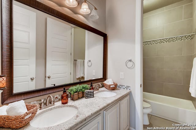 bathroom featuring a sink, toilet, and double vanity