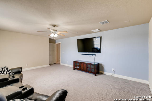 carpeted living area featuring visible vents, baseboards, a textured ceiling, and a ceiling fan