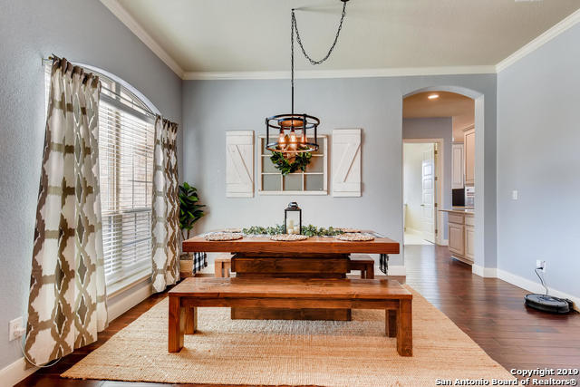 dining area with dark wood-type flooring, baseboards, arched walkways, and ornamental molding