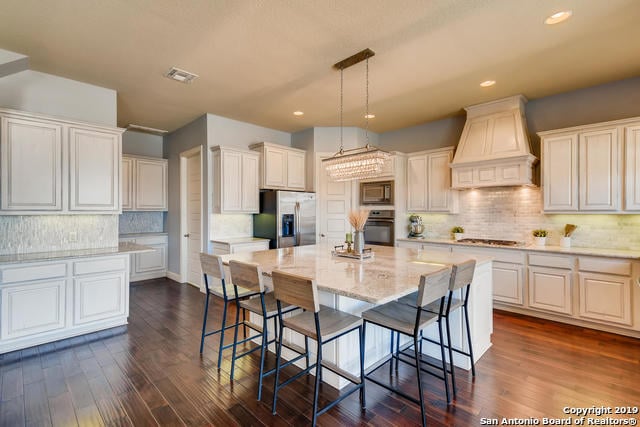 kitchen with visible vents, a breakfast bar, custom range hood, dark wood-style floors, and appliances with stainless steel finishes