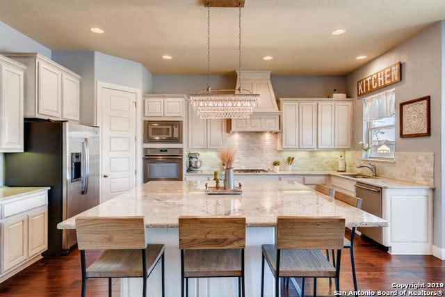 kitchen with backsplash, a kitchen island, a breakfast bar area, light stone counters, and appliances with stainless steel finishes