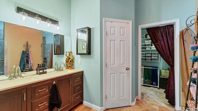 full bathroom featuring a sink, baseboards, double vanity, and tile patterned floors