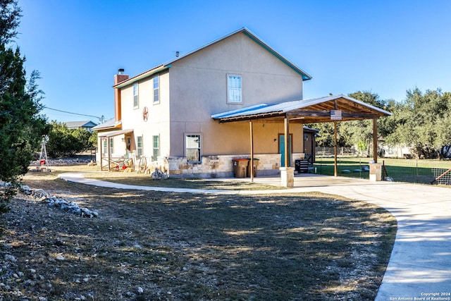 exterior space featuring a carport, stone siding, driveway, and a chimney