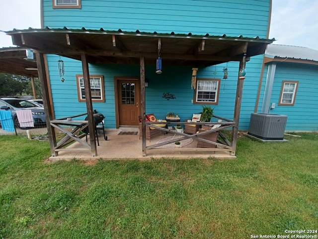 rear view of house with a patio area, central air condition unit, metal roof, and a yard