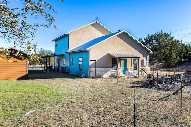 rear view of property with a yard, central AC, metal roof, and fence