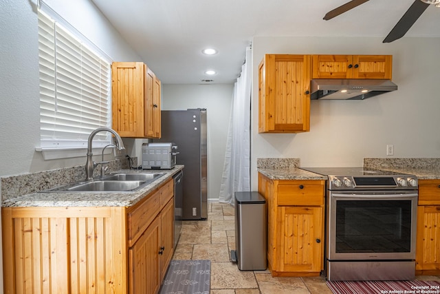 kitchen with a ceiling fan, under cabinet range hood, a sink, stone tile flooring, and stainless steel appliances