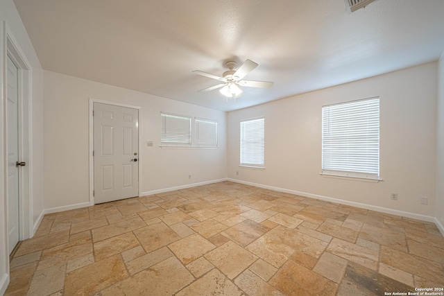 unfurnished room featuring ceiling fan, baseboards, and stone tile flooring