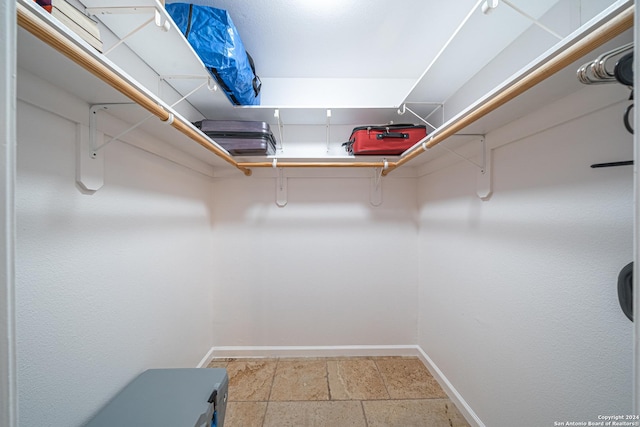 walk in closet featuring stone tile flooring