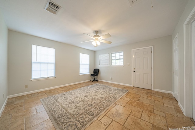 foyer with ceiling fan, visible vents, baseboards, and stone tile flooring