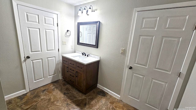 bathroom with vanity, stone finish flooring, and baseboards