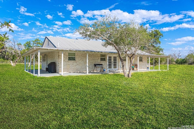 rear view of house featuring a lawn, french doors, and a patio