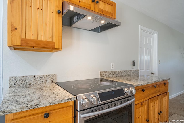 kitchen with electric stove, light stone countertops, baseboards, and under cabinet range hood