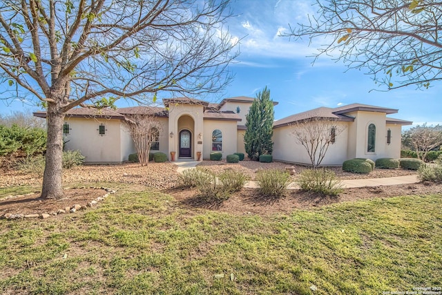 mediterranean / spanish house featuring a front lawn and stucco siding