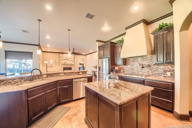 kitchen featuring visible vents, a spacious island, custom exhaust hood, a sink, and stainless steel appliances