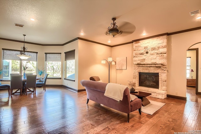 living area with a stone fireplace, visible vents, and wood-type flooring