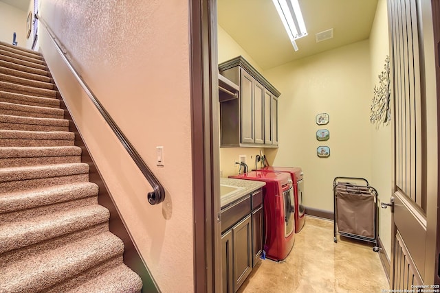 clothes washing area with visible vents, cabinet space, baseboards, and washer and clothes dryer