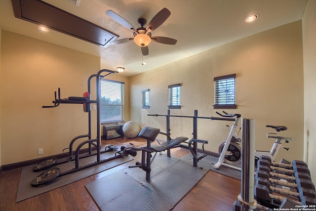 exercise room with plenty of natural light, attic access, wood finished floors, and a ceiling fan