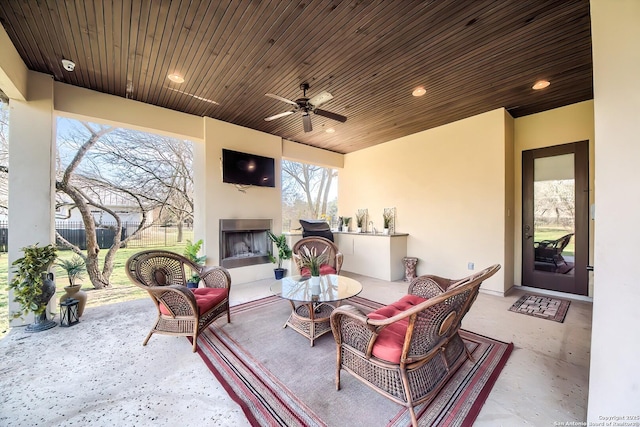 view of patio with an outdoor living space with a fireplace, a ceiling fan, and fence