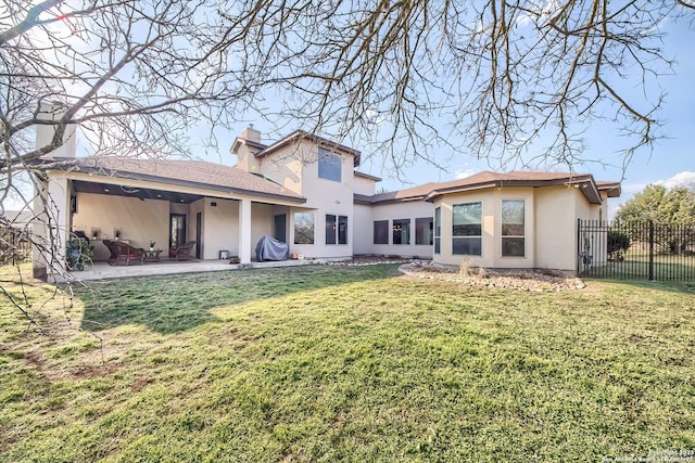 back of property with fence, a yard, a chimney, stucco siding, and a patio area