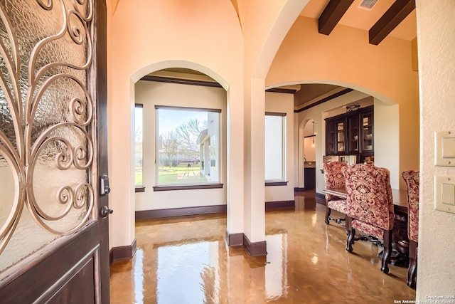 entrance foyer featuring beamed ceiling, visible vents, concrete floors, and baseboards