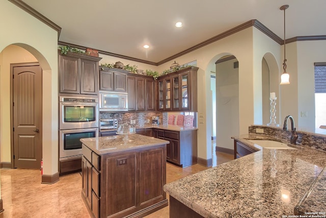 kitchen with white microwave, a kitchen island, a toaster, stainless steel double oven, and a sink