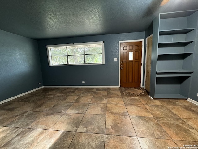 foyer with a textured ceiling and baseboards