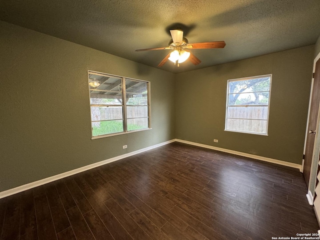 empty room featuring ceiling fan, baseboards, a textured ceiling, and dark wood-style floors