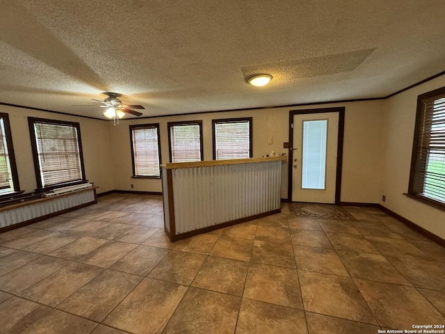 interior space featuring ceiling fan, a textured ceiling, crown molding, and baseboards