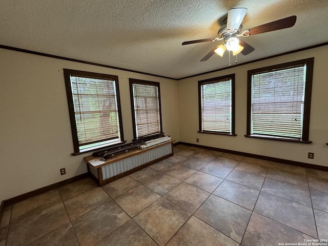 tiled spare room with a textured ceiling, a ceiling fan, baseboards, and ornamental molding