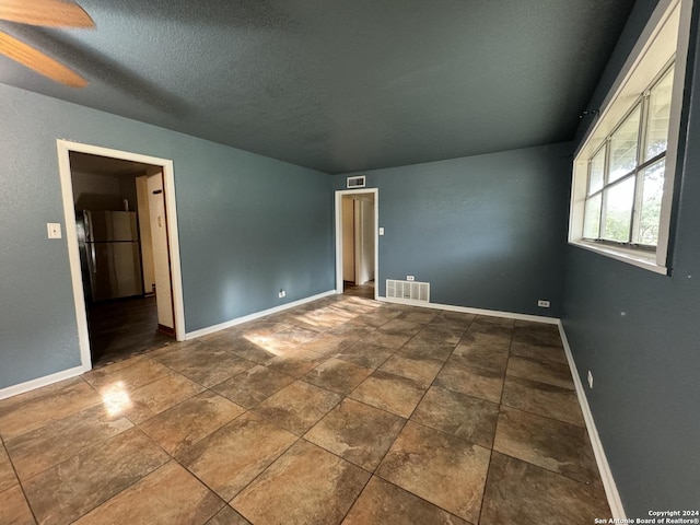 empty room with visible vents, baseboards, and a textured ceiling