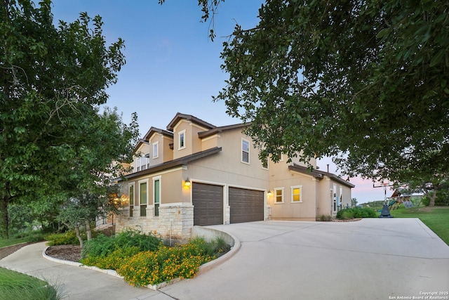 view of front of house featuring concrete driveway, a garage, stone siding, and stucco siding