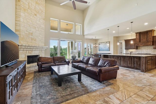 living area featuring a stone fireplace, recessed lighting, a ceiling fan, and a towering ceiling