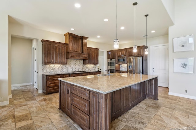 kitchen with a sink, backsplash, stainless steel appliances, dark brown cabinetry, and a large island with sink
