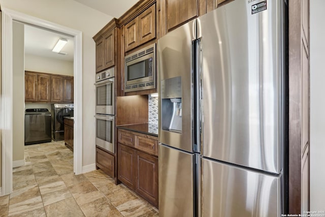 kitchen featuring tasteful backsplash, dark countertops, stainless steel appliances, separate washer and dryer, and baseboards