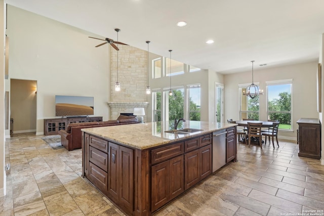 kitchen with a sink, plenty of natural light, a large fireplace, and stainless steel dishwasher