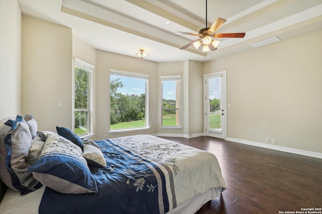 bedroom with visible vents, a tray ceiling, wood finished floors, baseboards, and access to exterior