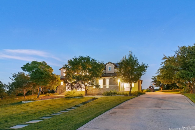 view of property hidden behind natural elements with stucco siding, concrete driveway, and a front lawn