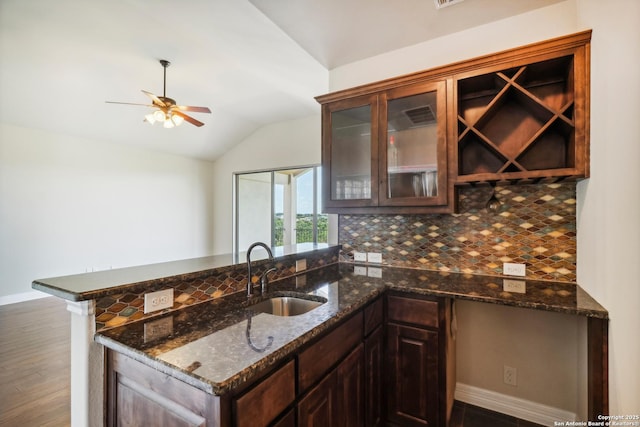 kitchen with lofted ceiling, a peninsula, ceiling fan, a sink, and backsplash
