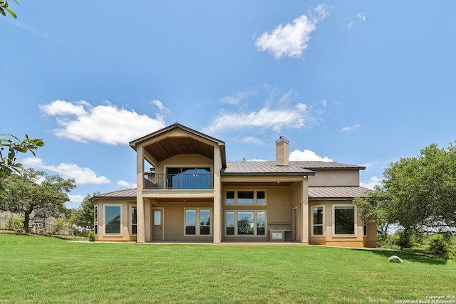 rear view of house featuring a yard, a balcony, metal roof, and a standing seam roof