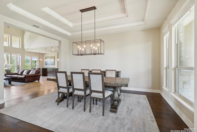 dining space with visible vents, baseboards, dark wood finished floors, a tray ceiling, and a chandelier