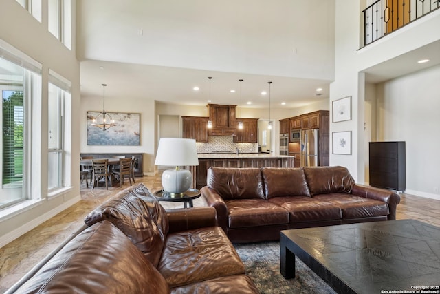 living area featuring a chandelier, a healthy amount of sunlight, and a high ceiling