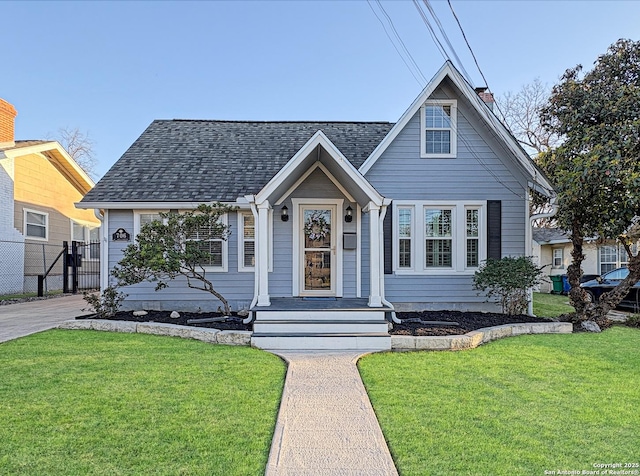 bungalow-style home with a front lawn, roof with shingles, and a chimney