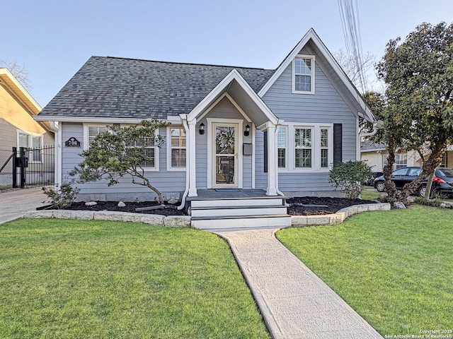 bungalow-style house with a shingled roof and a front lawn