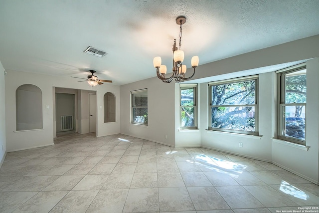 spare room with ceiling fan with notable chandelier, visible vents, a wealth of natural light, and a textured ceiling