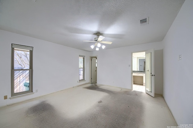 empty room with visible vents, light carpet, a textured ceiling, and a healthy amount of sunlight