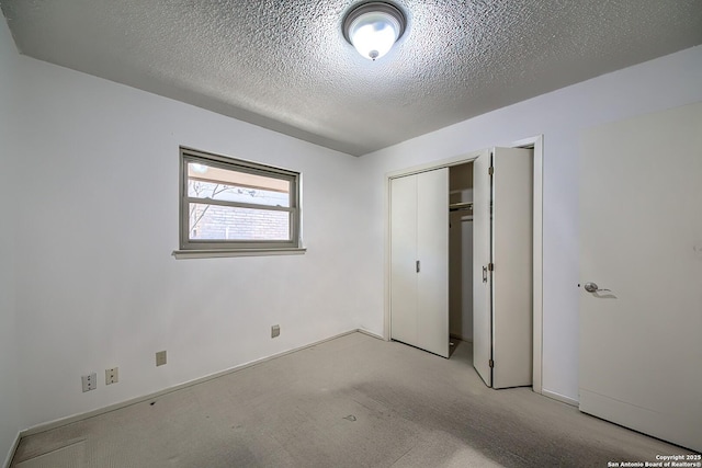 unfurnished bedroom featuring light carpet, a textured ceiling, and a closet