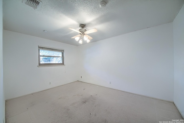 empty room featuring visible vents, a textured ceiling, and a ceiling fan