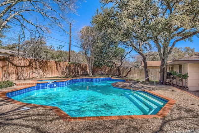 view of pool with a pool with connected hot tub, a fenced backyard, and a patio area