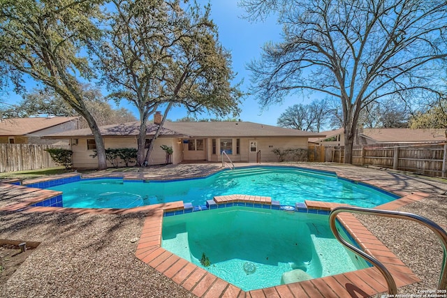 view of swimming pool featuring a patio, a fenced backyard, and a pool with connected hot tub