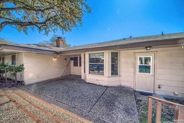 exterior space with a chimney and a shingled roof